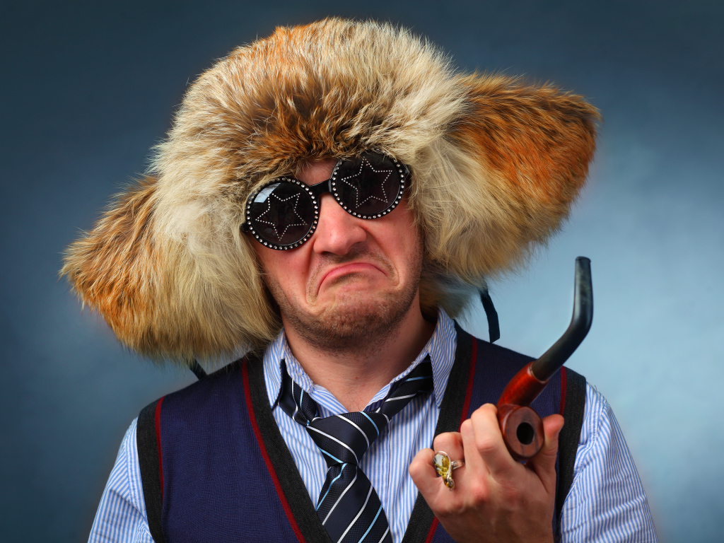 Мужчина в меховой шапке в модных очках с трубкой в руке