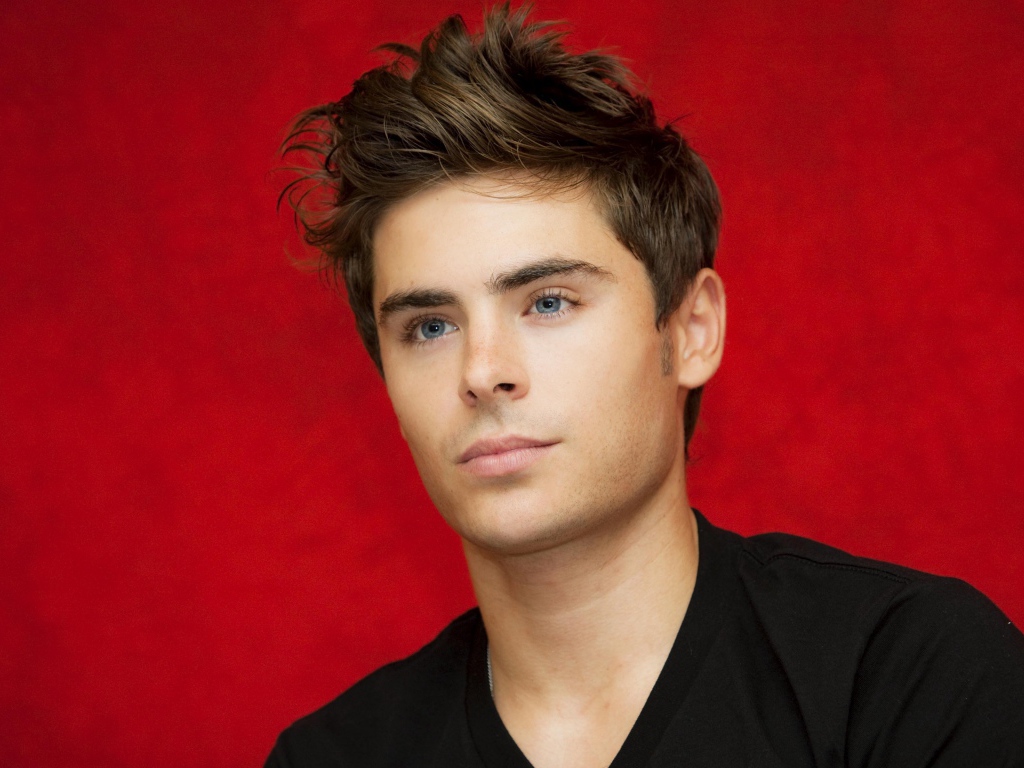 Голубоглазый актер Зак Эфрон на красном фоне