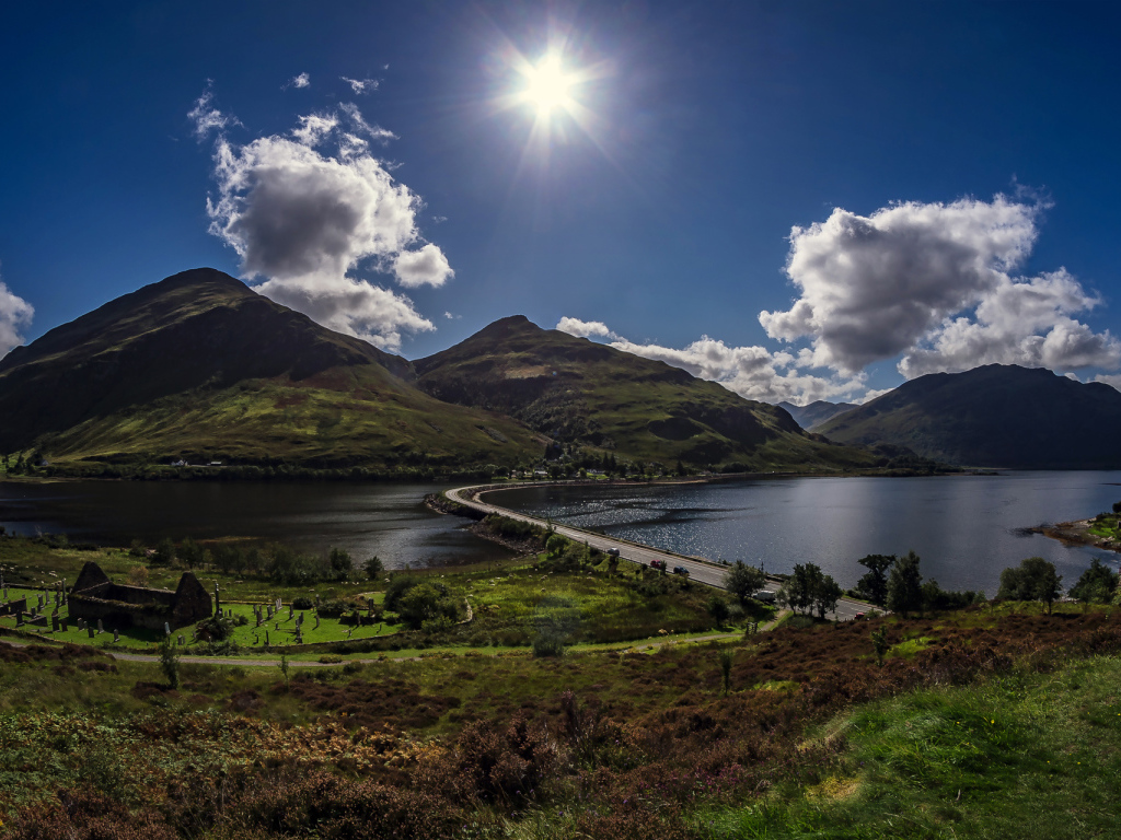Яркое солнце в голубом небе над горами у реки