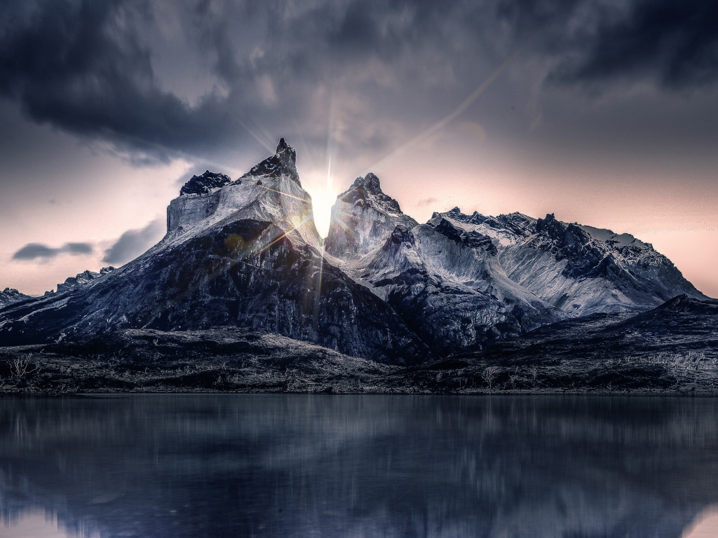 Рассвет солнца над горами у озера под пасмурным небом