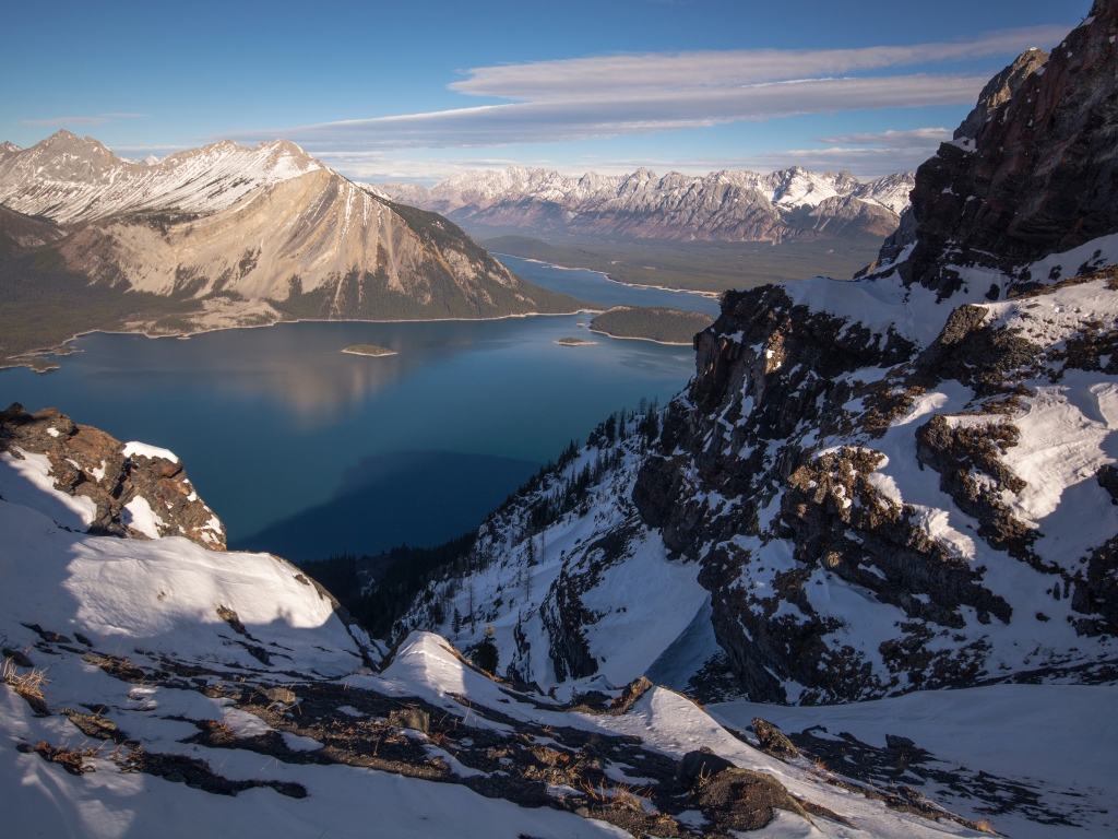 Озеро между заснеженных гор на фоне голубого неба