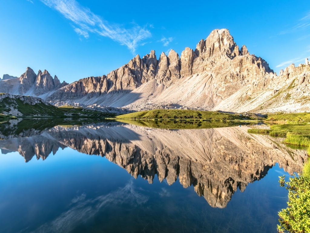 Горы и голубое небо отражаются в чистой воде 
