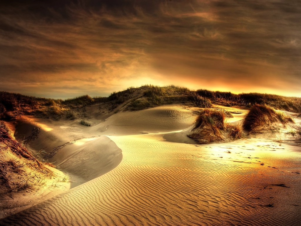 Волнистый песок под красивым небом на закате