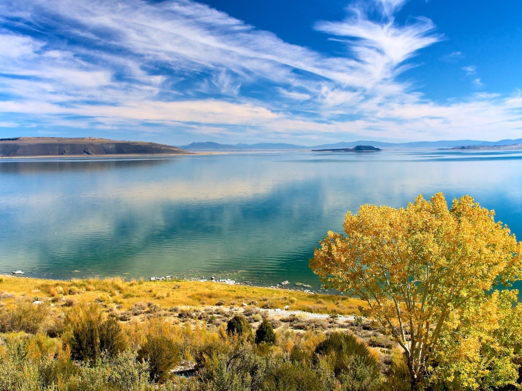 Белые облака в голубом небе отражаются в озере