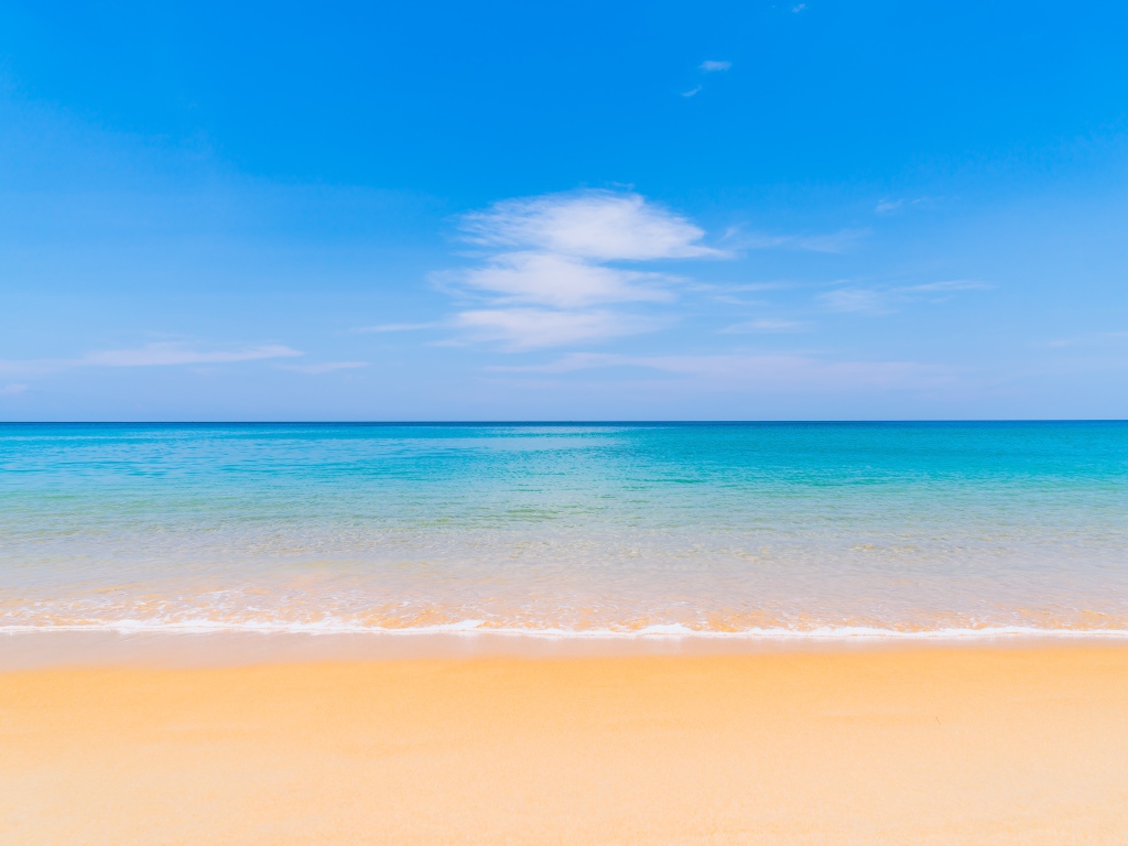 Желтый песок у лазурного океана под голубым небом
