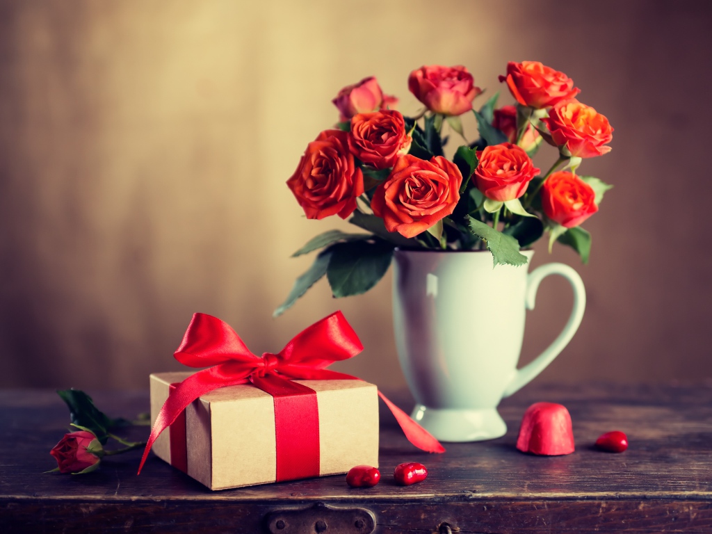 Букет роз в белой вазе с подарком на столе