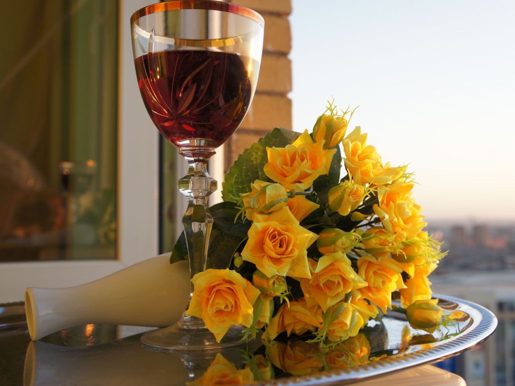 Букет желтых роз на столе с бокалом вина