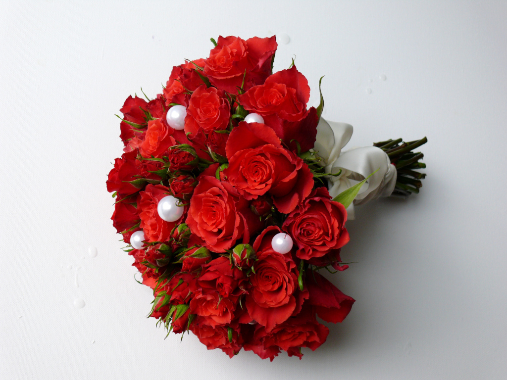 Красивый букет красных роз с жемчужными бусинами на сером фоне