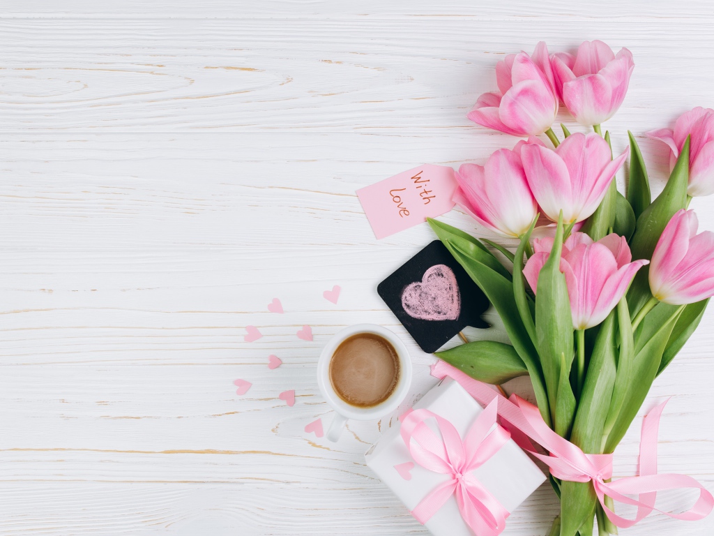Букет розовых тюльпанов на столе с чашкой кофе и подарком 