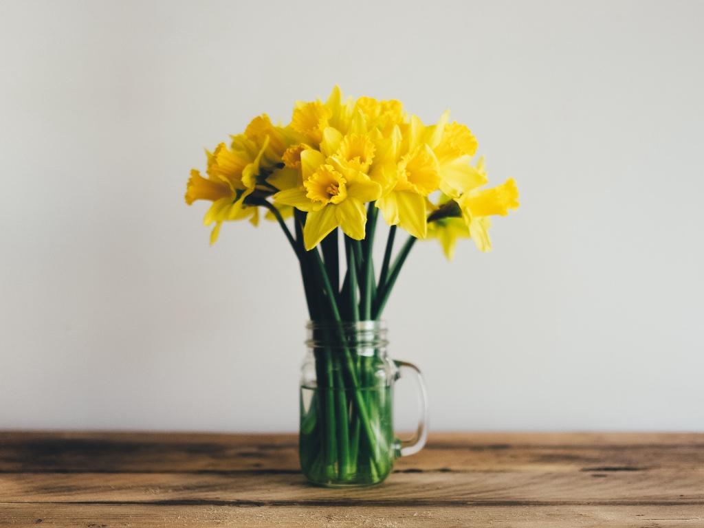 Букет желтых нарциссов в стеклянной вазе на столе 