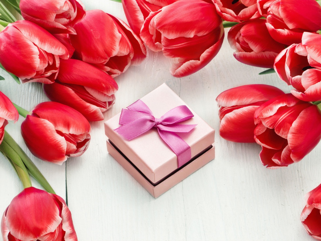 Красные тюльпаны на деревянной поверхности с подарком