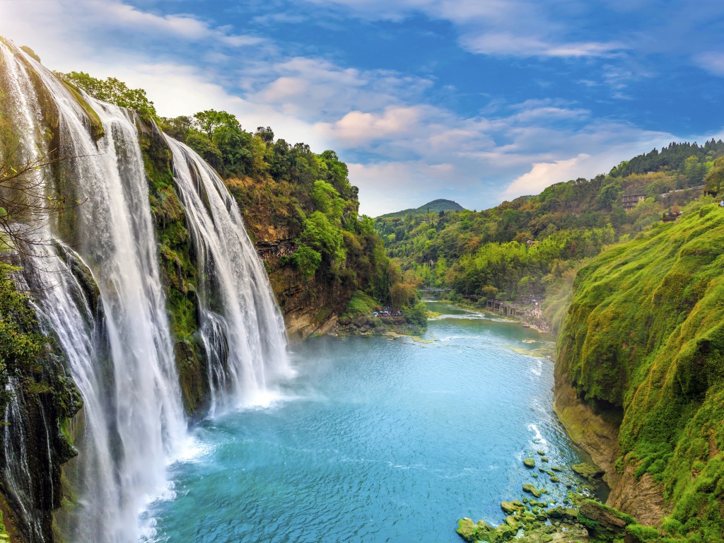 Красивый водопад стекает с утеса под голубым небом