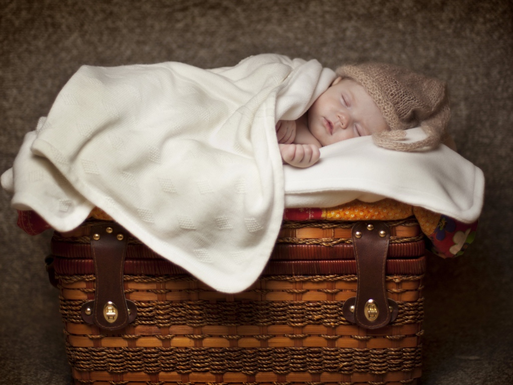Грудной ребенок спит на плетеной корзине