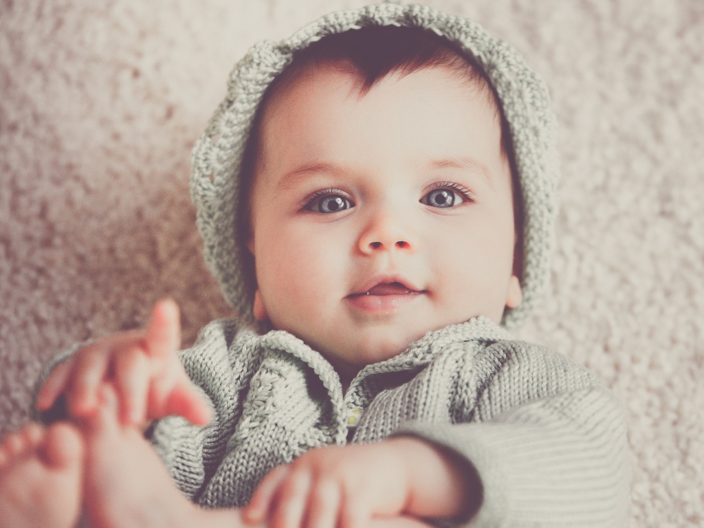 Маленький милый голубоглазый малыш в вязаном костюме