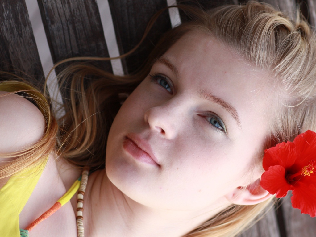 Девочка с красным цветком гибискуса в волосах