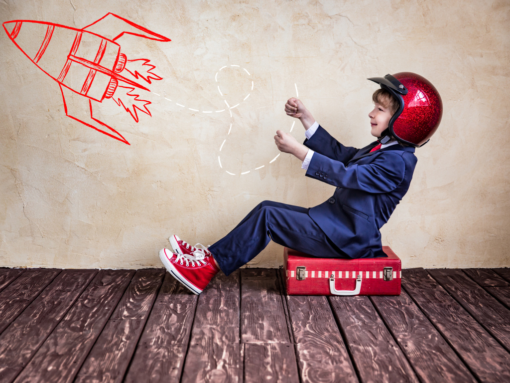 Маленький мальчик в шлеме сидит на чемодане