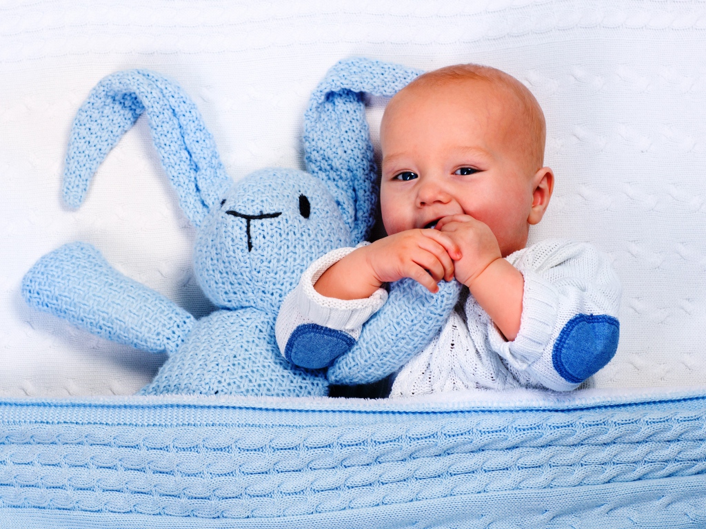 Маленький грудной ребенок грызет мягкую игрушку 