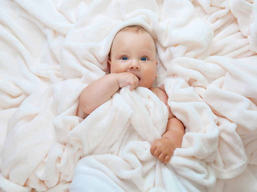Маленький голубоглазый ребенок в покрывале 