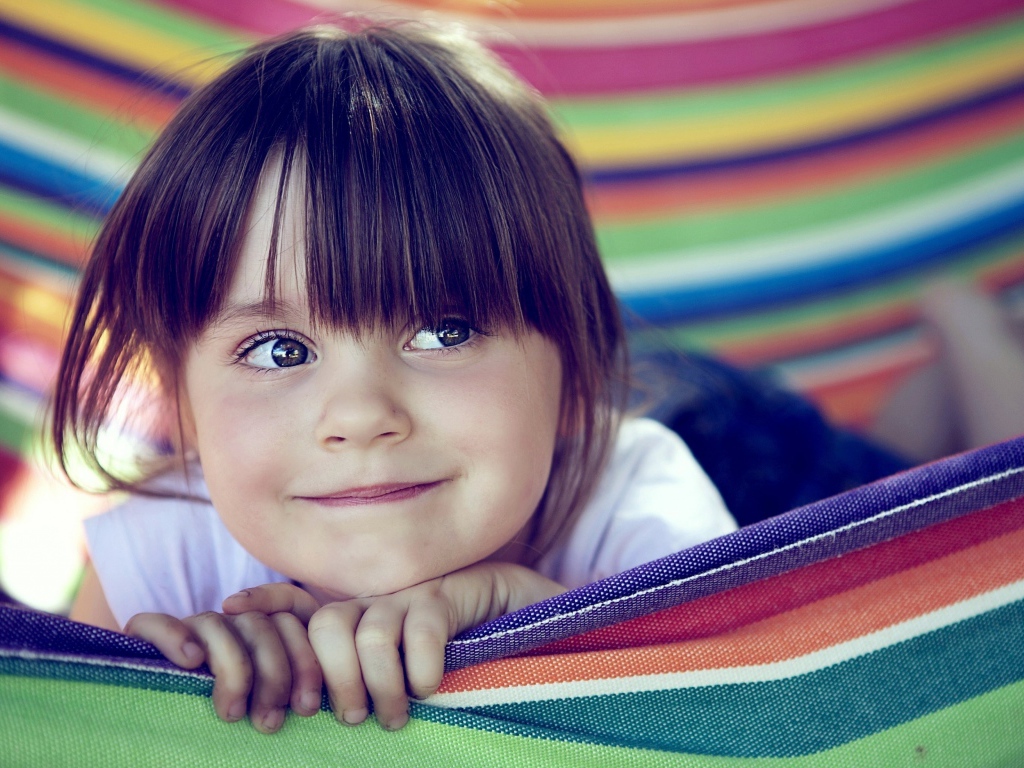 Маленькая кареглазая девочка лежит в гамаке