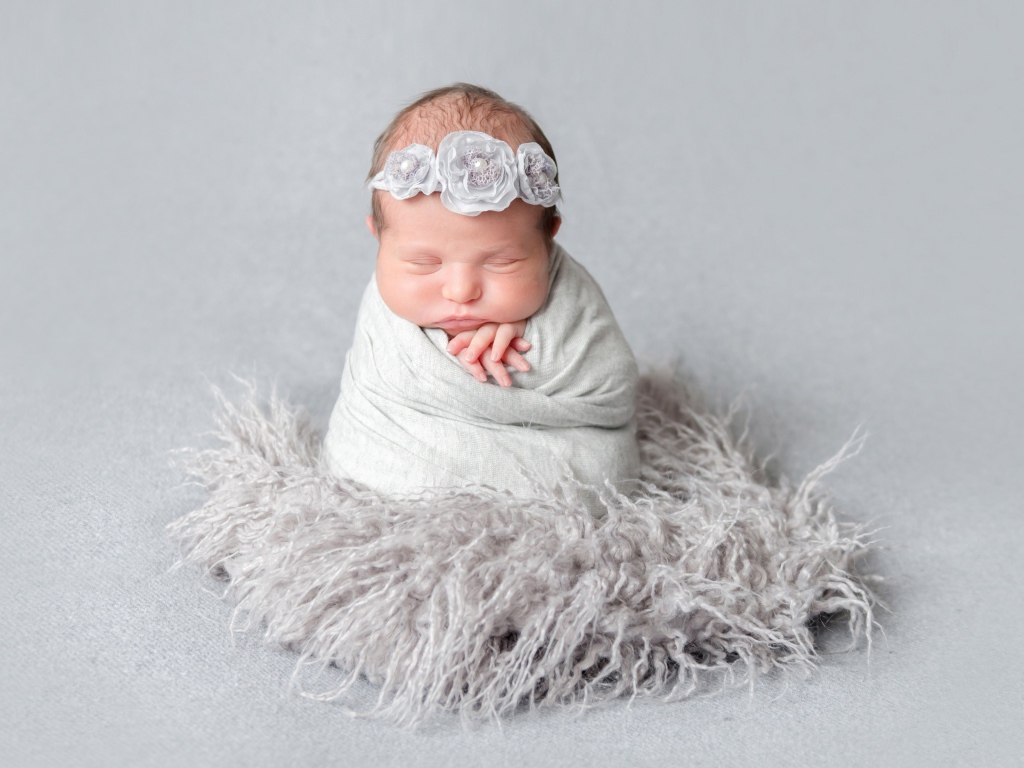 Маленький спящий младенец на сером фоне