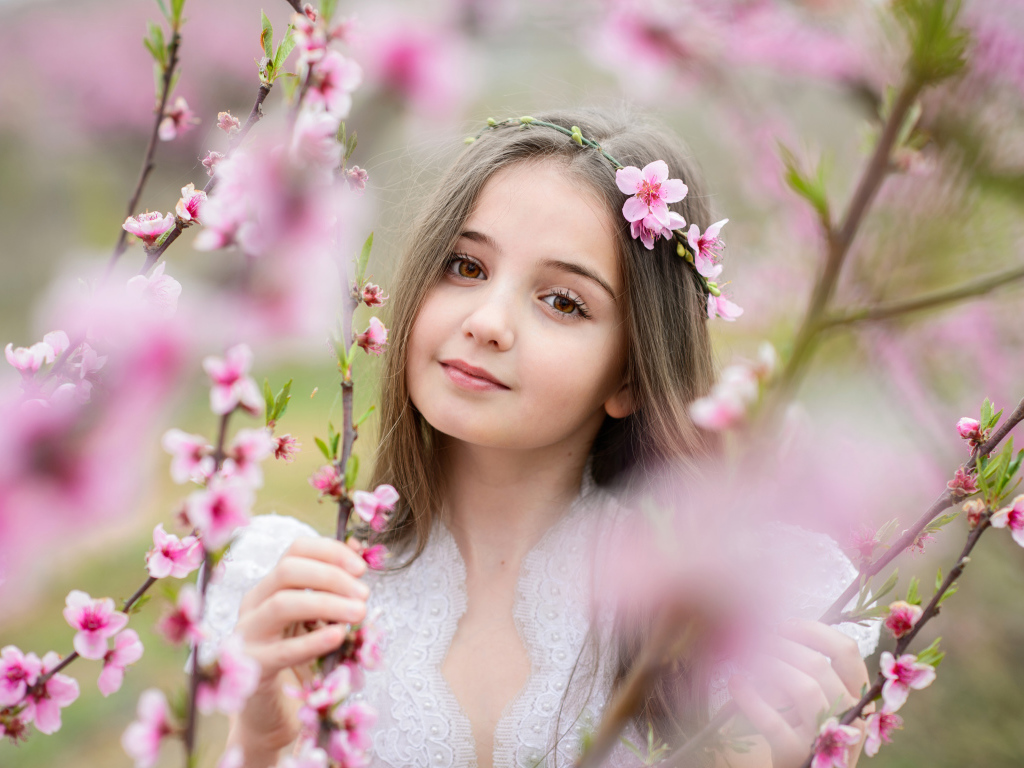 Красивая кареглазая девочка с розовыми цветами на дереве