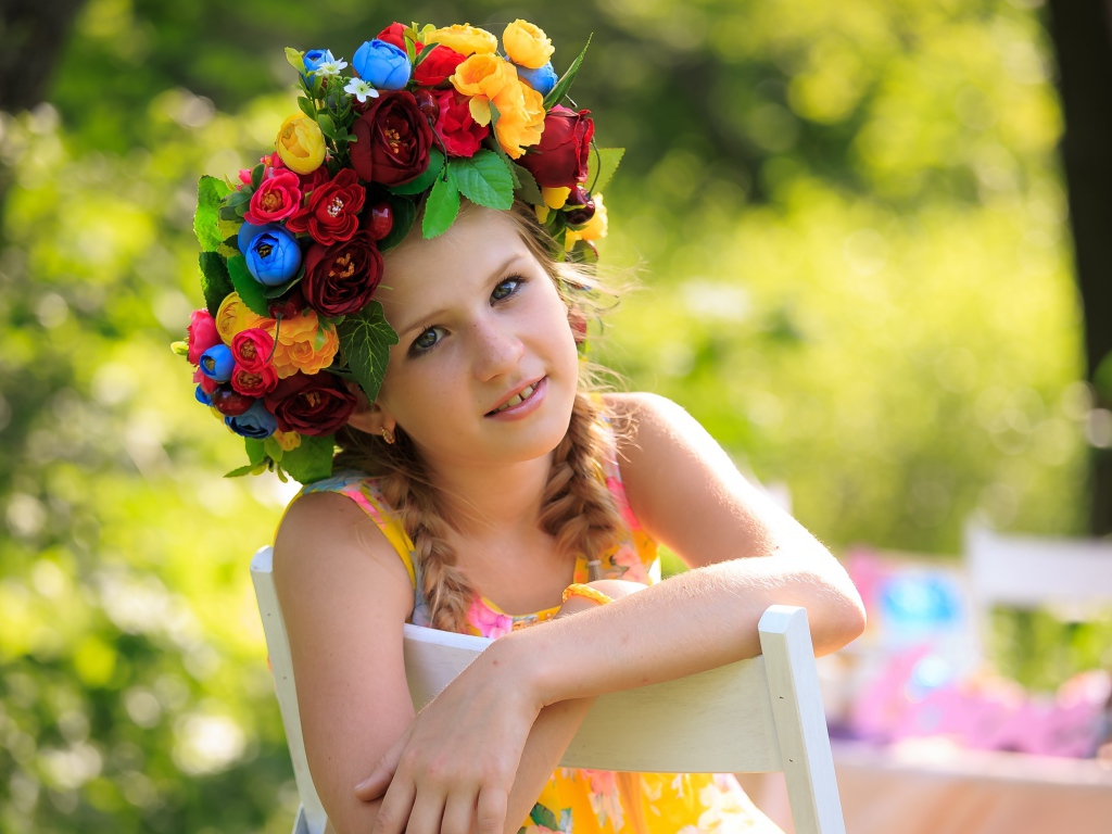 Красивая девочка с венком на голове сидит на стуле