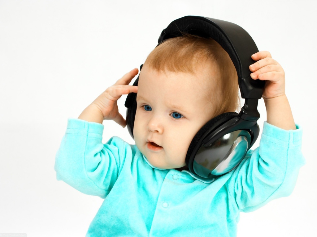 Голубоглазый мальчик в больших наушниках на белом фоне