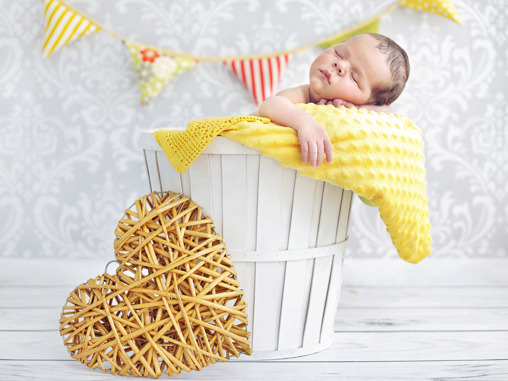 Маленький ребенок спит в корзине с плетеным сердцем