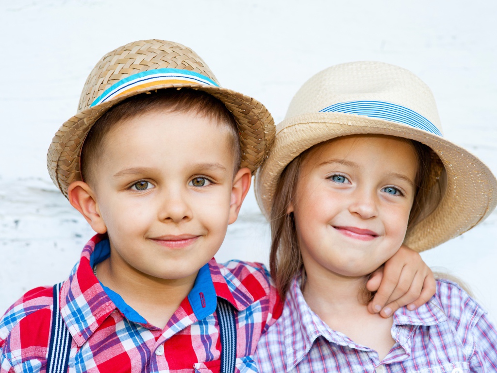 Маленькие мальчик и девочка в соломенных шляпах на пляже