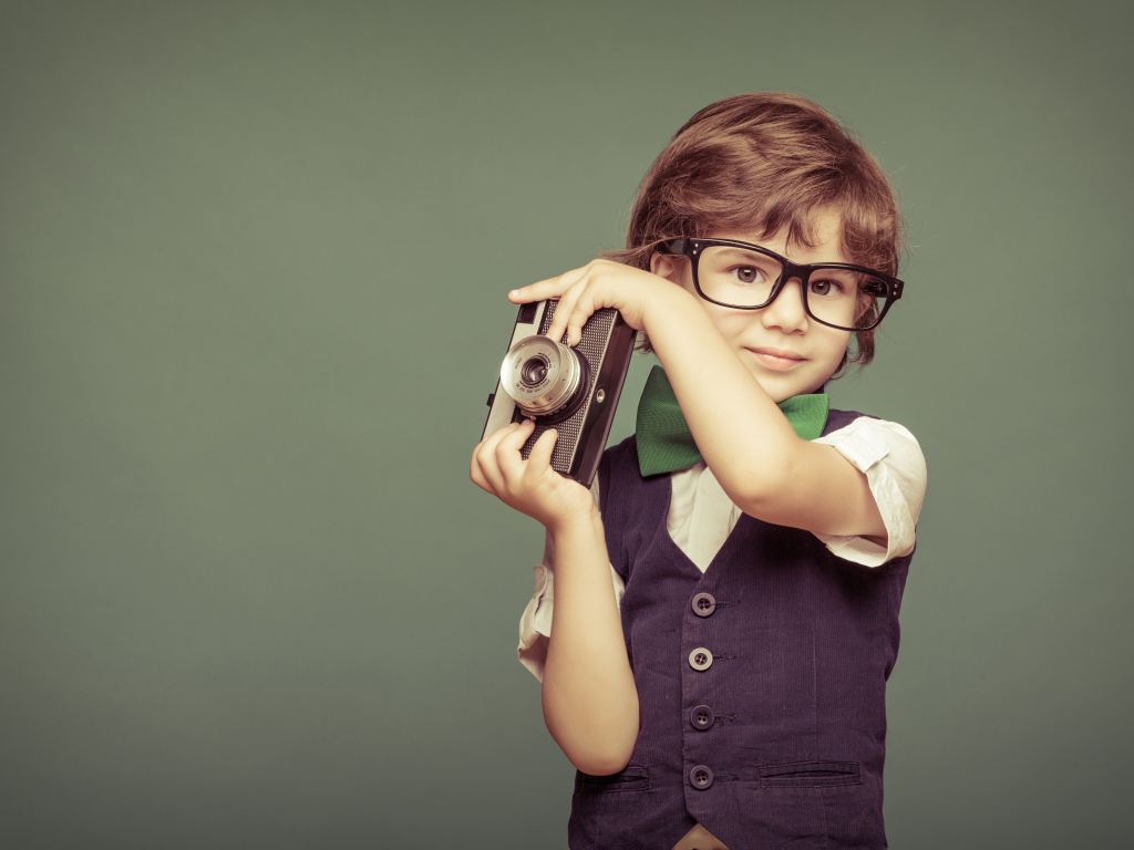 Маленький мальчик в очках с фотоаппаратом