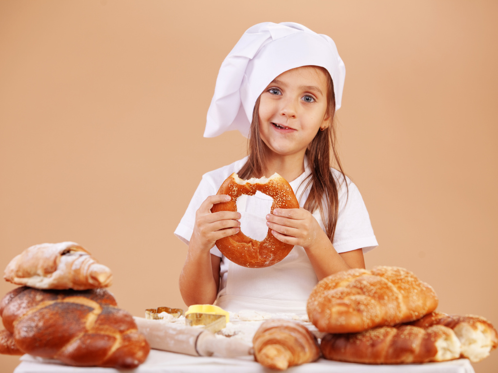 Маленькая девочка в костюме повара и свежей выпечкой