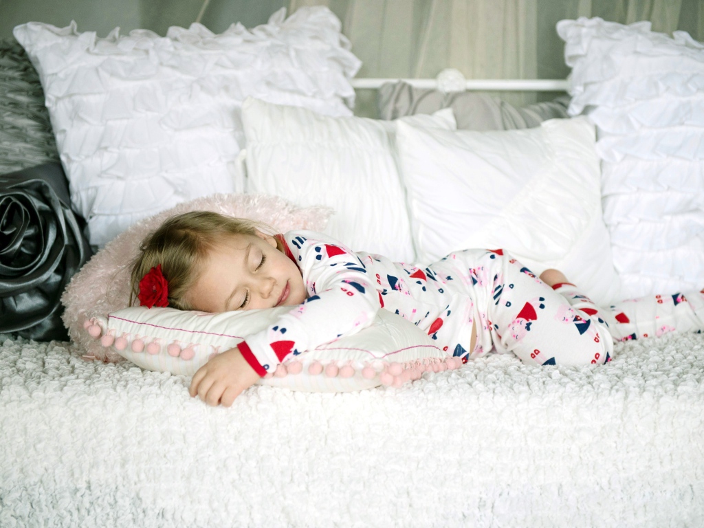 Маленькая девочка спит на подушке