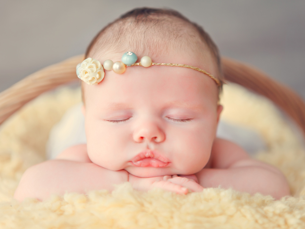 Спящая грудная девочка с красивым украшением на голове