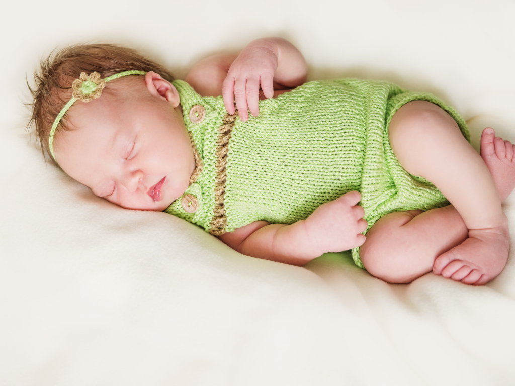 Спящий младенец в вязаной одежде