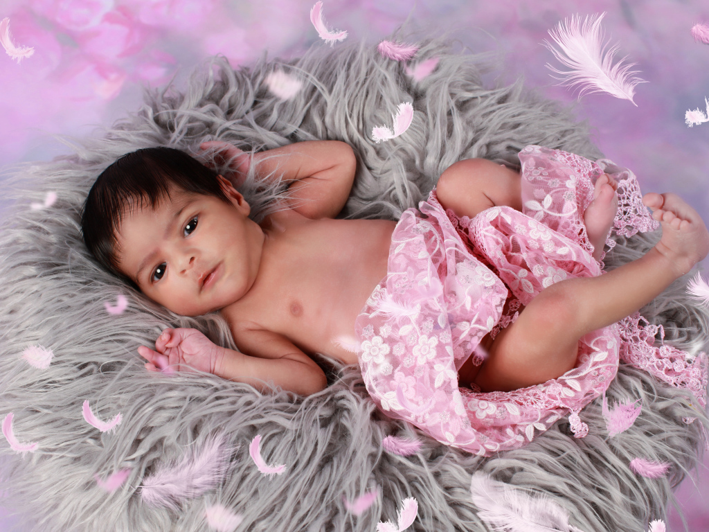 Младенец лежит на сером меховом покрывале 