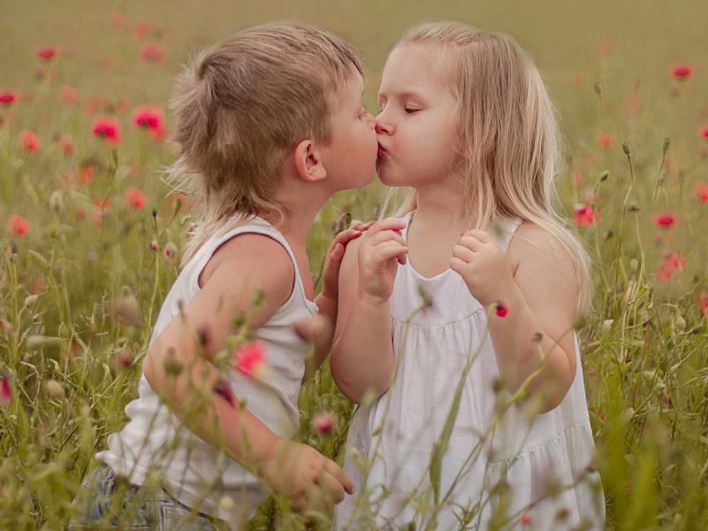 Первый поцелуй мальчика и девочки на цветущем поле
