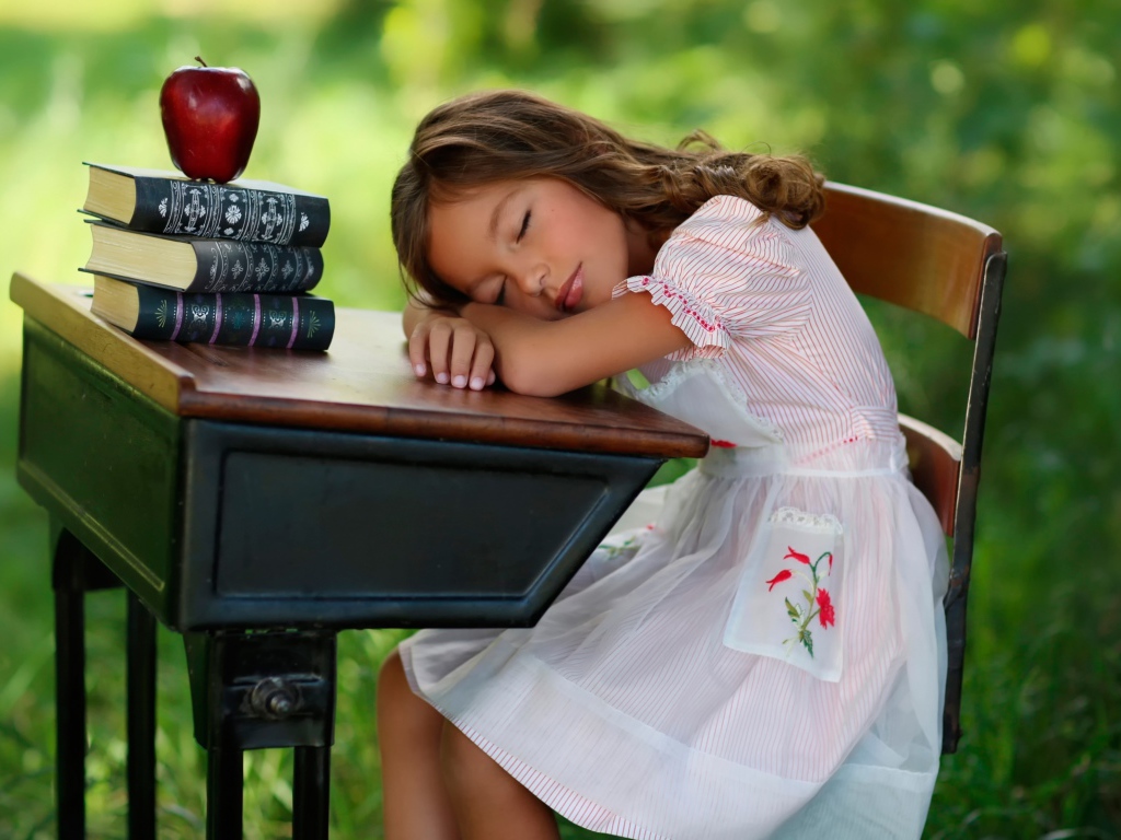 Уставшая маленькая ученица уснула за партой