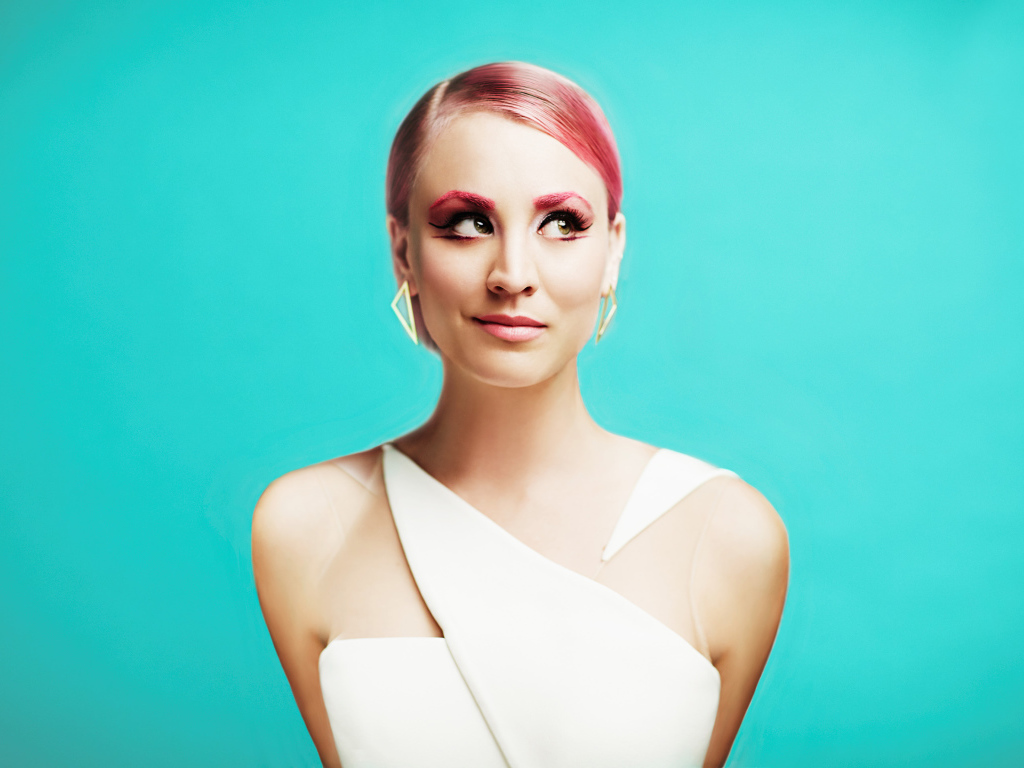 Актриса Кейли Куоко с ярким макияжем на голубом фоне