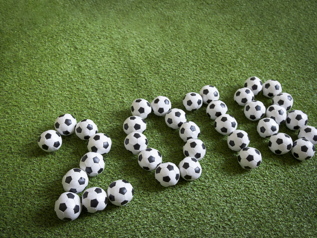 Цифры 2018 из футбольных мячей на зеленой траве