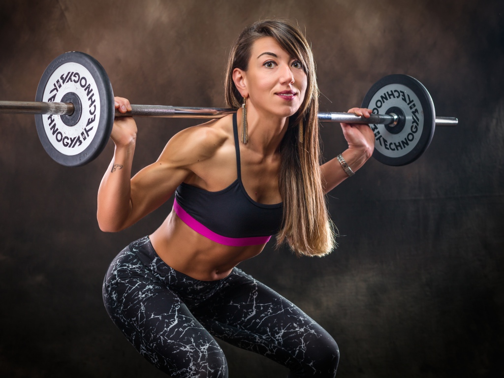 Спортивная накаченная девушка со штангой 