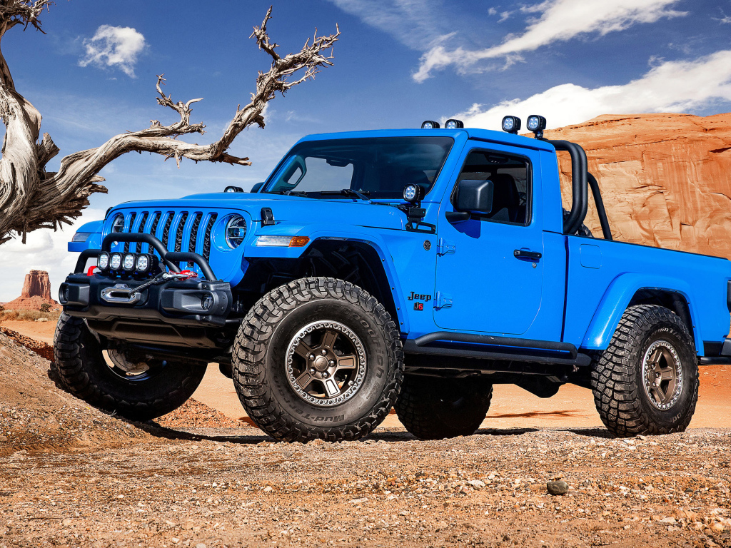 Синий пикап Jeep J6, 2019 года на фоне гор у сухого дерева