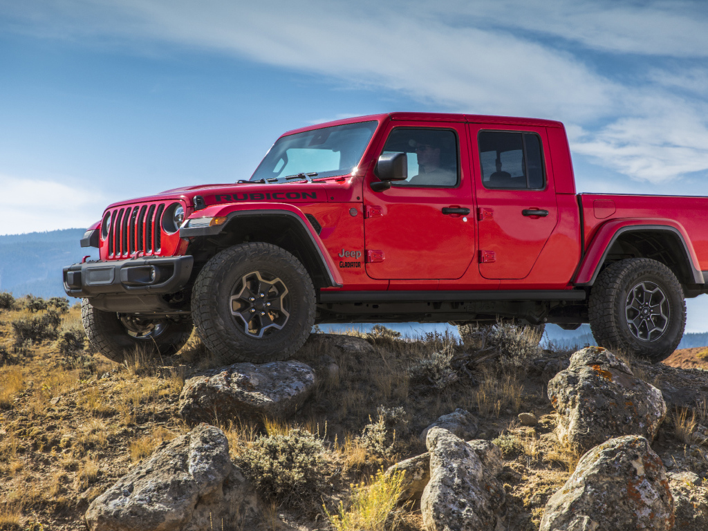 Красный пикап Jeep Gladiator Rubicon на холме с камнями