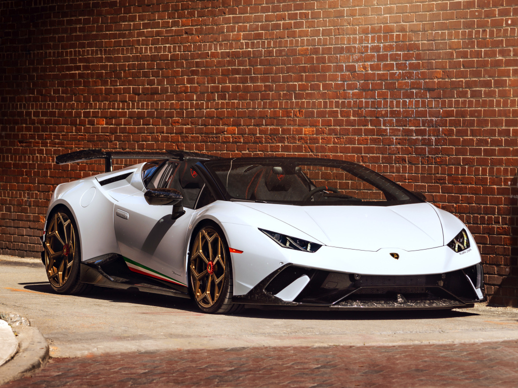 Белый быстрый Lamborghini Huracan стоит у кирпичной стены