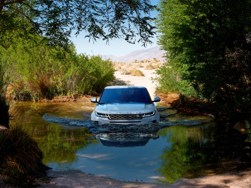 Белый внедорожник Range Rover Evoque едет по воде 