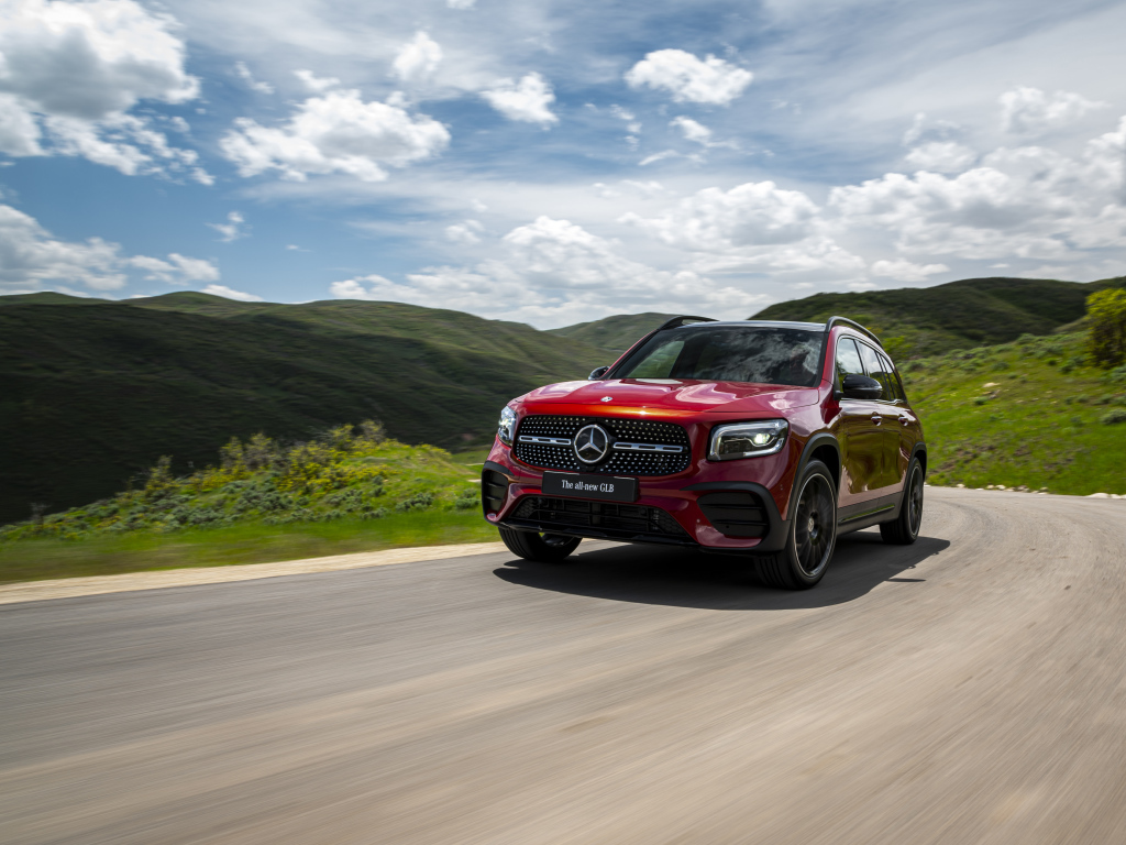 Красный автомобиль Mercedes-Benz GLB-Class  на фоне зеленых холмов