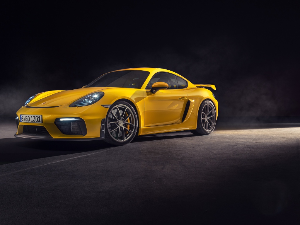 Желтый спортивный автомобиль Porsche 718 Cayman GT4, 2019 года на сером фоне