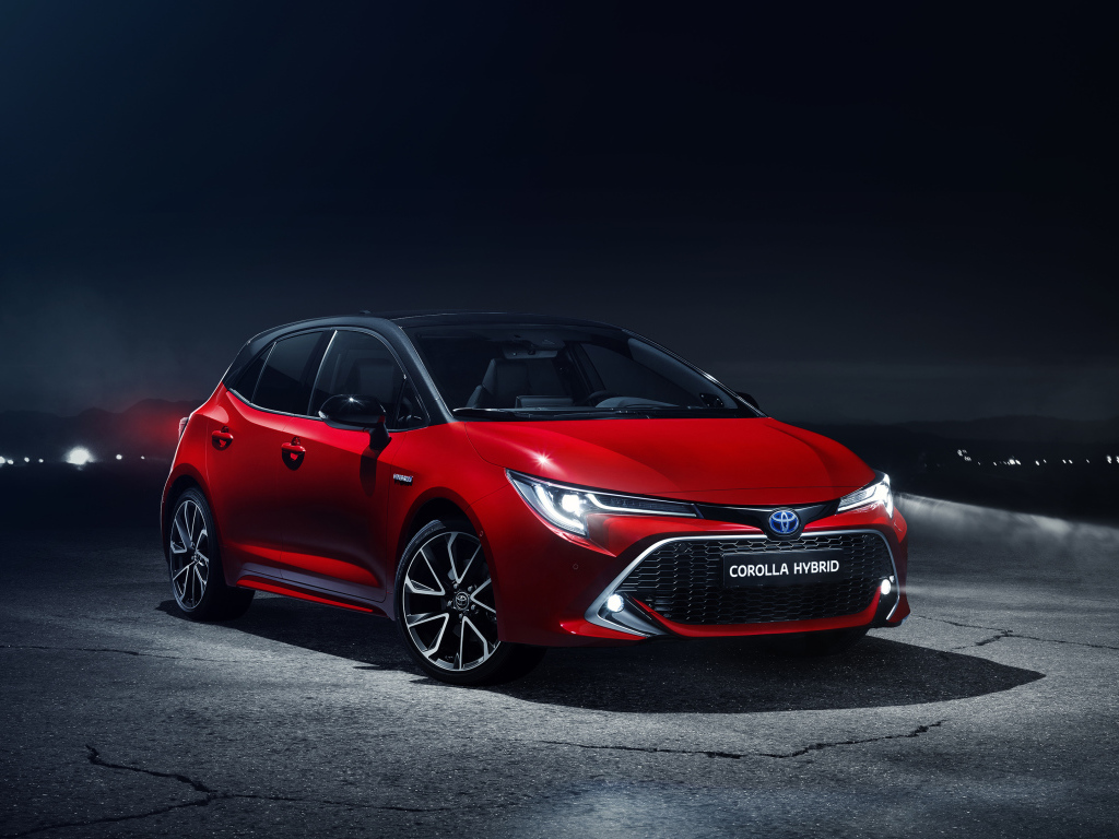 Красный автомобиль Toyota Corolla Hybrid 2018 года в свете фонарей