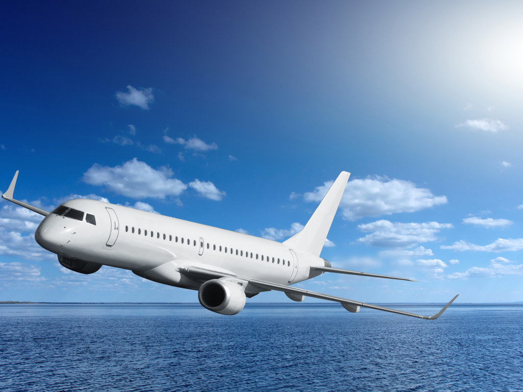 Большой белый пассажирский самолет летит над морем