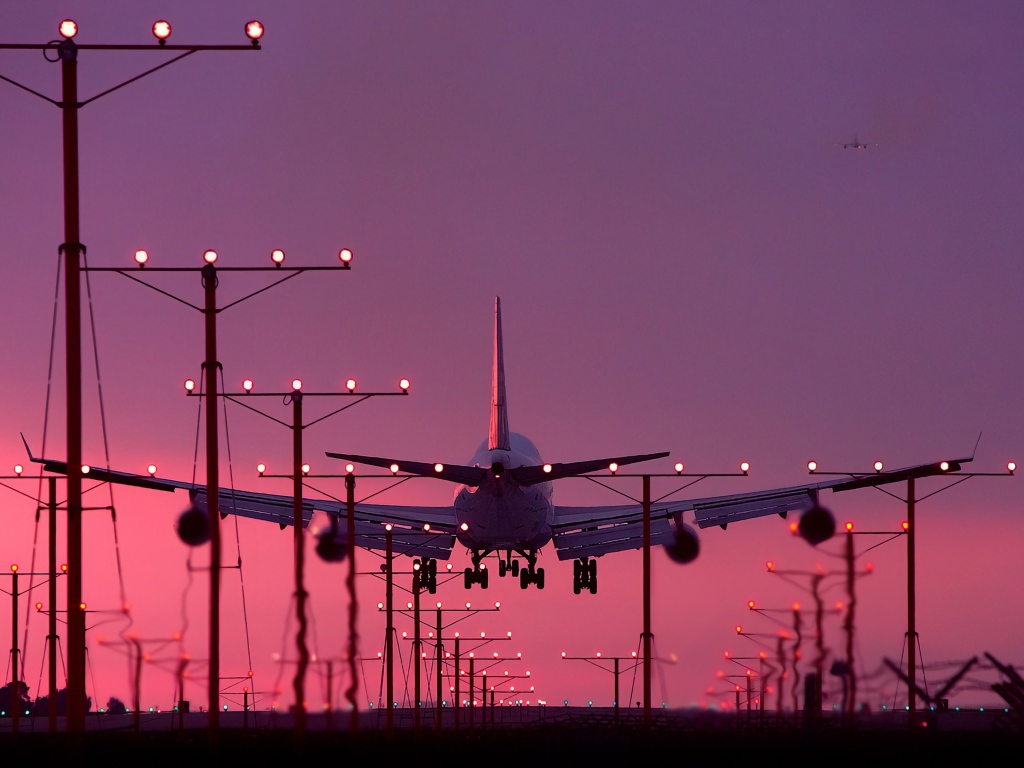 Пассажирский самолет идет на посадку на закате 