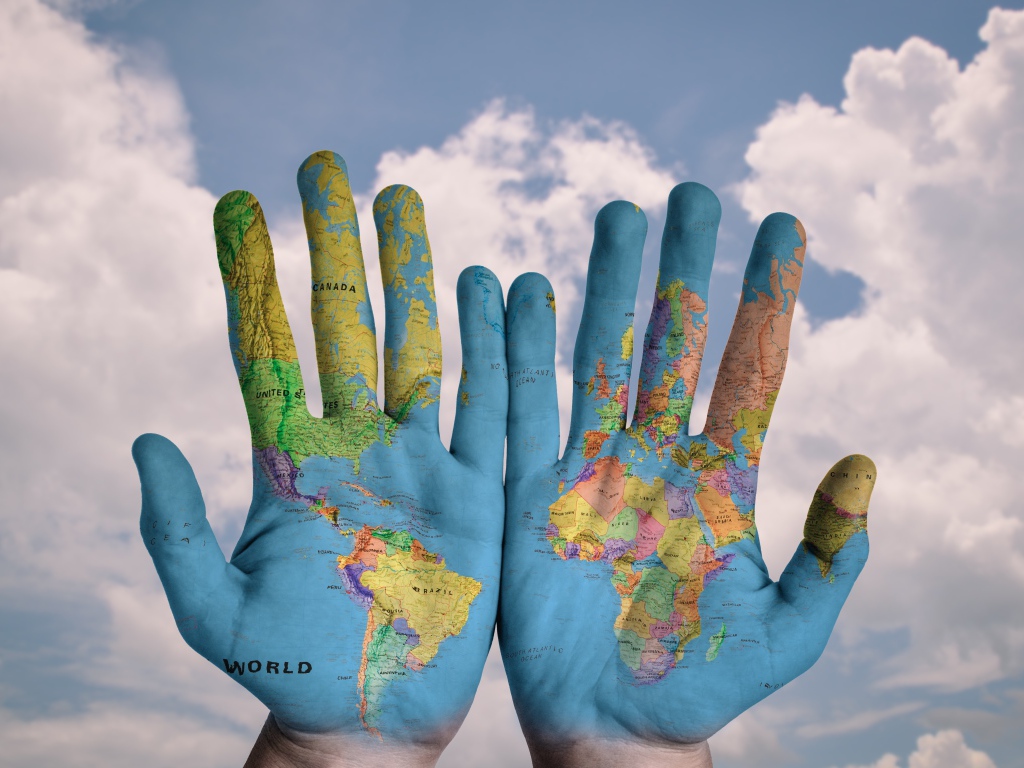 Карта мира нарисована на ладонях на фоне неба